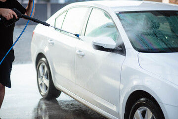 Fototapeta na wymiar Summer car wash. Cleaning the car using high pressure water. Car wash with soap. Close up concept. Close up photo of a man hands washes his car Concept disinfection and antiseptic cleaning. Car wash.