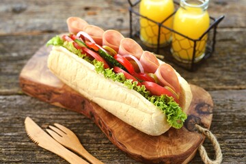Homemade turkey ham sandwich with tomato, cucumber, red onion, olives, lettuce, cheese and white sauce.