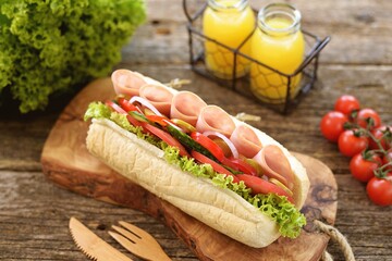 Homemade turkey ham sandwich with tomato, cucumber, red onion, olives, lettuce, cheese and white sauce.