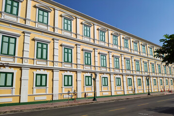 Fototapeta na wymiar Yellow building with green windows in sunny day