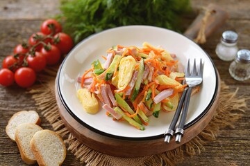 Salad of egg pancakes, smoked ham, cucumber and pickled carrots.