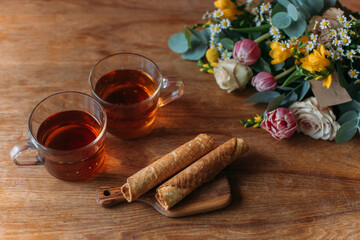 Still life. Table with mugs of tea, cookies and flowers