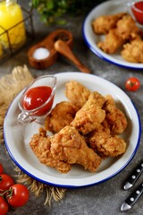 Delicious homemade deep fried breaded chicken wings with tomato sauce on a gray background.