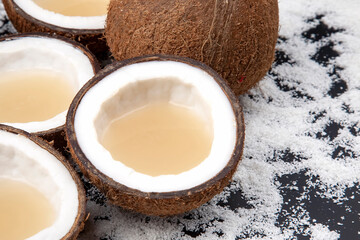 cut fresh coconut with real coconut milk on a background of coconut flakes. vitamin fruits. healthy food