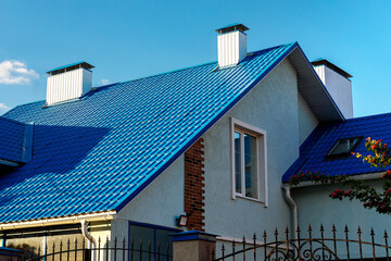 Roof of a house or cottage made of blue metal tiles with drains, slopes, tides, chimney against the...