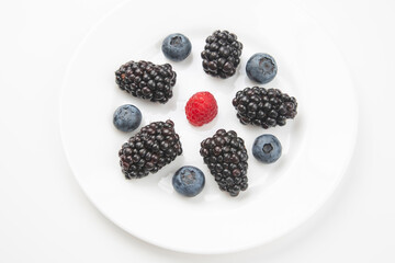 blueberries, raspberries and blackberries on a white plate