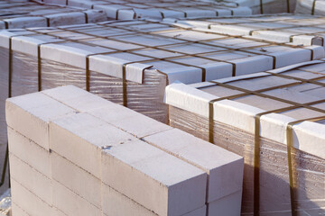 Silicate brick on wooden pallets wrapped in transparent plastic wrap at a construction site