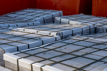 Paving slabs on wooden pallets wrapped in transparent plastic wrap at a construction site