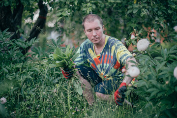 A man works in the garden, flying weeds, tending the lawn