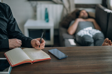 Psychotherapist and patient at an appointment in the office. Doctor's hands with notepad