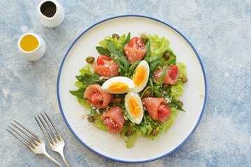 Fototapeta na wymiar Salad with salted salmon, cherry tomatoe, lettuce, arugula, capers, egg, parmesan, olive oil and lemon juice. Healthly food.