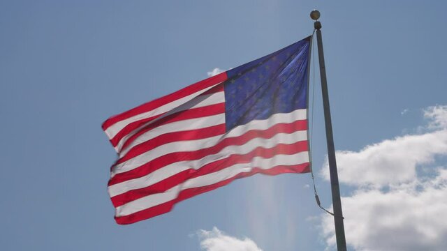 American Flag blowing in the wind with a blue sky background, sunny windy day