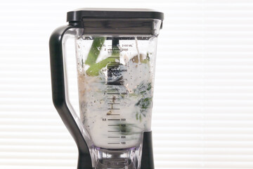 Mixing ingredients in blender. Celery spinach banana smoothie recipe.