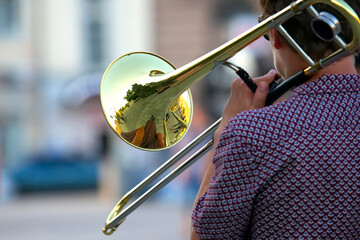 Reflection of the street in the instrument solo trumpet. male musician plays the trombone. music and creativity. jazz and Blues
