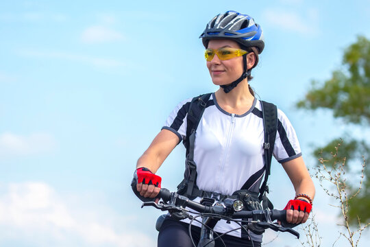 Beautiful and happy girl cyclist with a bike on nature. Healthy lifestyle and sports. Leisure and hobbies