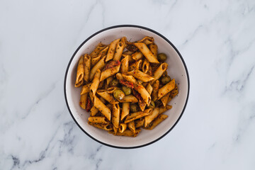 plant-based food, vegan penne pasta with sundried tomatoes and olives with herbs