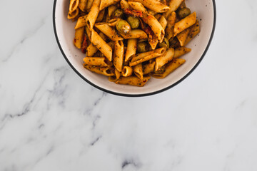 plant-based food, vegan penne pasta with sundried tomatoes and olives with herbs