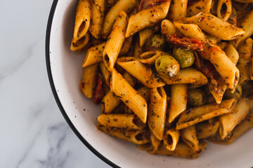 plant-based food, vegan penne pasta with sundried tomatoes and olives with herbs