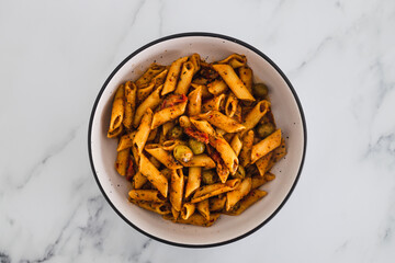 plant-based food, vegan penne pasta with sundried tomatoes and olives with herbs
