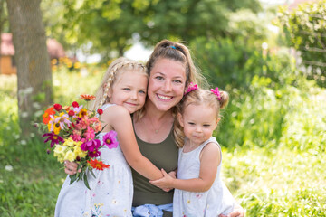 Young mom with two little girls and a bouquet of summer flowers