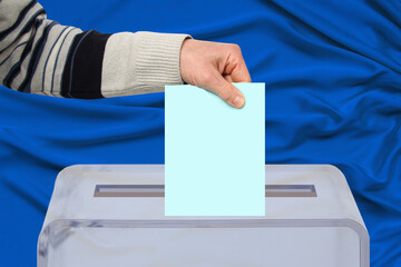 male hand of a voter lowers the ballot in a transparent ballot box on the background, concept of...