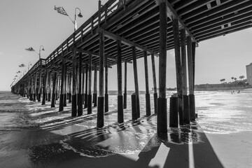Black and white view under the historic wood pier at Ventura beach in Southern California.  