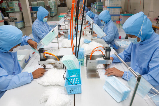 Factory workers are producing masks for protection against viruses.