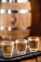 small dose glasses, high quality distilled alcohol. Brazilian cachaça (called pinga), dripping, with rustic wood brazil, bar image, old cellar.