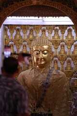 Fototapeta premium Close up face of buddha sculpture in the building of Wat San Pa Yang Luang temple with blurred people or tourism
