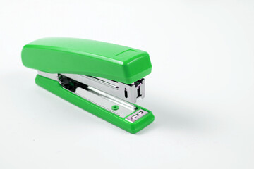 Green stapler with staples wires on white background.