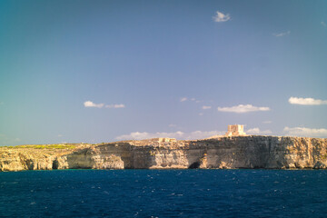 Naklejka premium Coast of the island of Comino with Saint Mary's Tower, layered limestone island in Malta