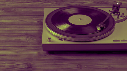A tinted image of a vinyl record player with the disc mounted on a wooden table.