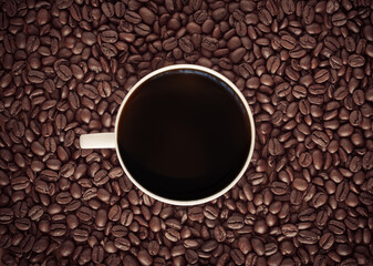 Black coffee cup with roasted coffee beans background.