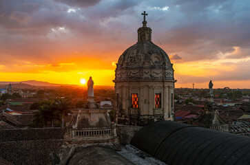Dome of the La Merced church in Granada at sunset with Virgin Mary sculptures and the city skyline,...