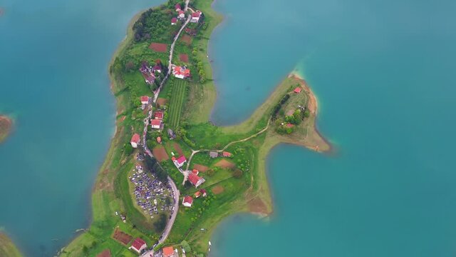 Birds eye view of a small village on the middle of Lake Rama. Clear blue water. Bosnia