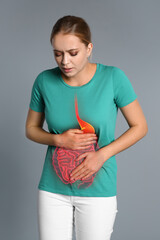 Woman suffering from stomach pain on grey background