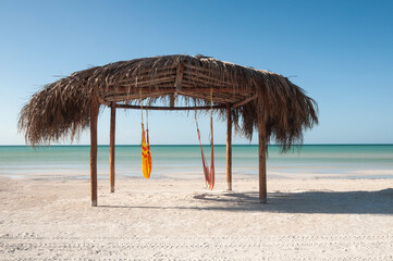 Fototapeta na wymiar Natural and tropical hut on the beach Caribbean Ocean Front, desert beach whit hammock on a beach in Holbox Island, Mexico
