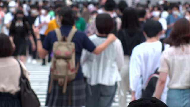 SHIBUYA, TOKYO, JAPAN - AUG 2020 : Back shot and crowd of people wearing surgical mask to protect from Coronavirus (COVID-19) at Shibuya Crossing. Shot in day time, hot summer season. Slow motion.