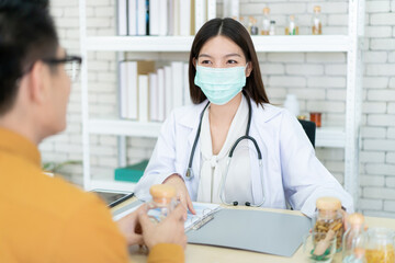 Asian specialist doctor talking to a patient in doctor office in hospital. Patient worried about his sickness and influenza come to a doctor and taking examination in hospital. Healthcare concept.