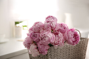 Basket with beautiful pink peonies in kitchen