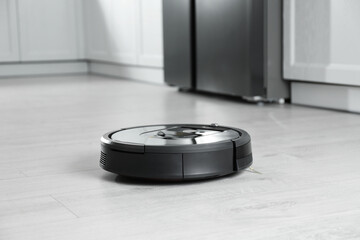 Modern robotic vacuum cleaner on floor in kitchen