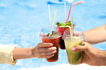 People with refreshing drinks in water park, closeup