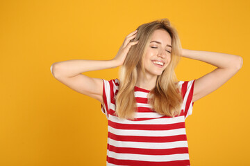 Portrait of beautiful young woman with blonde hair on yellow background