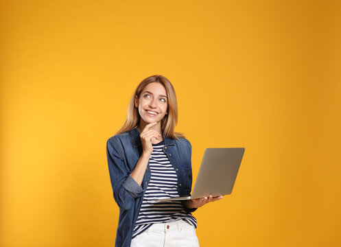 Portrait of woman with modern laptop on yellow background