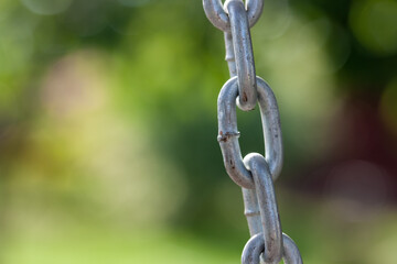 Steel chain links on yellow and green garden background