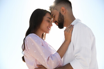 Happy young couple against blue sky, low angle view. Honeymoon trip