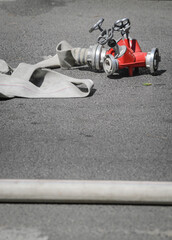 Firefighters hose and hydrant hose adaptor on concrete during a fire.