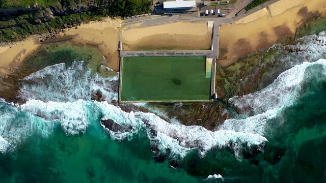 Lowering drone shot of ocean bathes at Merewether, New South Wales