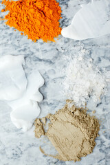 Creamy texture, salt, dry orange and light green powder pigmant for organic cosmetic on gray marble background. Texture. Close-up. Top view, curcuma powder ingredient