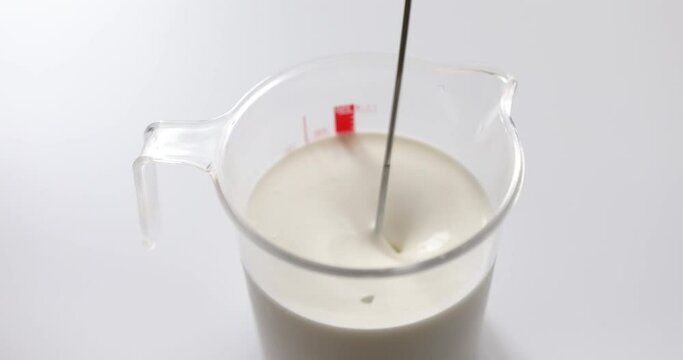 Stirring whipping cream with milk in measuring cup